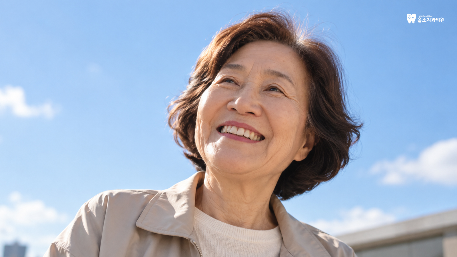 오른쪽 위에 판암동 치과 올소치과 로고가 있고, 푸른 하늘 아래 단발머리 어르신이 환하게 웃으며 위를 바라보는 모습